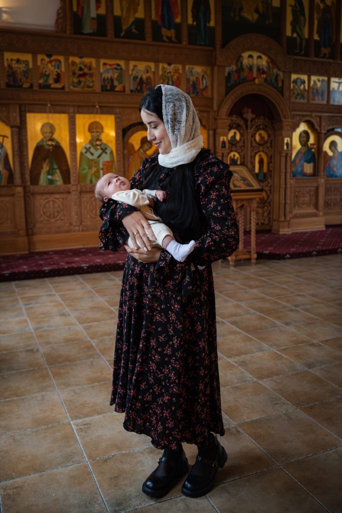 Женщина в тёмном платье держит младенца в храме